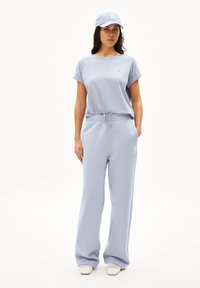 T-shirt oversized azzurro chiaro e joggers abbinati, entrambi in morbido tessuto. Presenta una cintura con cordino e un logo ricamato sul petto.