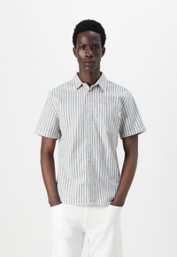 Camisa de manga corta de tejido ligero, con rayas verticales azules y blancas, un bolsillo en el lado izquierdo del pecho y cuello.