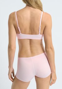 Ensemble brassière et culotte en rose clair, sans couture, avec bretelles ajustables. Texture lisse, design minimaliste et sans détails matériels visibles.
