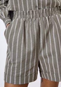 Pantalones cortos a rayas grises con cinturilla elástica, bolsillos laterales y dobladillos cortados, elaborados en un tejido ligero con un acabado texturizado.