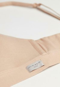 Lichtbeige zachte stoffen beha met een gladde textuur, verstelbare bandjes en een zilveren label met de tekst "intimissimi Natural."