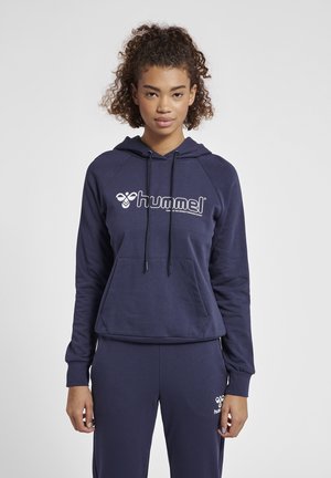 Granatowy hoodie z sznurkami, przednia kieszeń oraz białe logo "hummel". Tkanina wydaje się być miękka o gładkiej fakturze, w zestawie z dopasowanymi dresami.