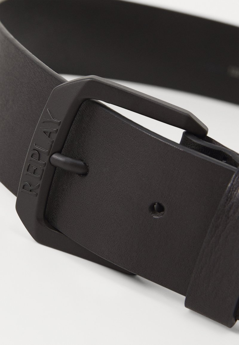 Schwarzer Leder-Gürtel mit einer mattschwarzen Metallschnalle, auf der "REPLAY" eingeprägt ist. Texturierte Oberfläche und mehrere sichtbare Verstellungslöcher.