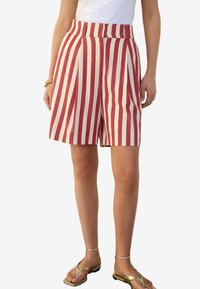 Rød- og hvidstribede shorts med høj talje, plisseringer og løs pasform, lavet af let materiale. Sammen med guld sandaler.