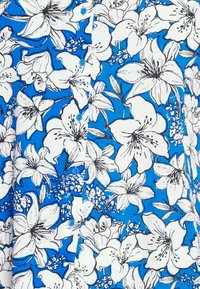 Motif floral blanc avec des contours noirs sur un tissu de chemise bleu vif à boutons.
