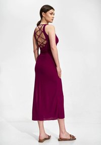 Mauve długa sukienka z dopasowanym topem i krzyżującym się detalem z tyłu. Gładki, lekki materiał i boczne rozcięcie podkreślają design.
