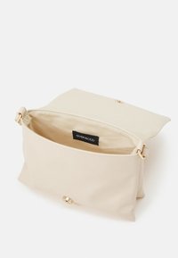 Beige syntetisk väska med flap stängning och guldfärgade detaljer. Inuti är den fodrad; har en varumärkesetikett. Enkel rektangulär form.