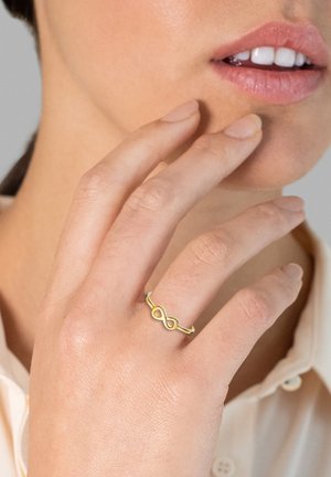 Gul uendelighedsring vist på en finger, med en glat, poleret overflade og et delikat, minimalistisk design uden yderligere dekorationer.