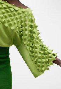 Pullover verde con ruches testurizzati e tridimensionali sulle maniche, realizzato in un morbido tessuto a maglia e con un collo scollato a spalle scoperte.