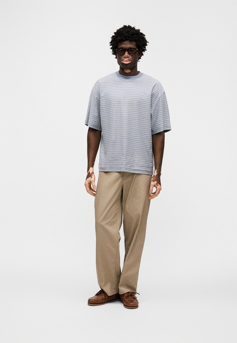 Gray and blue striped short-sleeve shirt, beige trousers, brown shoes; relaxed fit, soft texture, with visible stitching and collar detail.