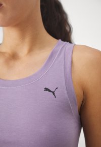 Heledad lavendelvärviline tanki, millel on sile tekstuur, musta Puma logo rinnal ja ümarkaelus.