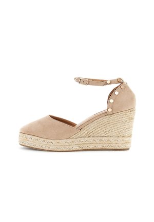 Beige ruskind kilehæl espadrille sandal med ankelrem, guldspænde og nittebesætning på plateauhælen.