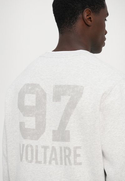 Hallhallaneem puuvillane dressipluus, mille seljal on suur, kulunud trükk "97 VOLTAIRE". Ümar kaelus, soonikkoes mansetid ja ääred.