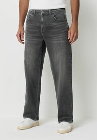 Szare dżinsy o prostym kroju, z pięcioma kieszeniami i subtelnym efektom przecierania, połączone z białymi sneakersami.