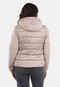 Giacca a sacco beige chiaro con cappuccio, caratterizzata da cuciture trapuntate, una superficie liscia e polsini elastici. La vista posteriore mostra un design aderente.