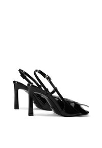 Slingback con tacco a stiletto in vernice nera con punta appuntita, sottile cinturino regolabile e tacco alto. Texture liscia e design minimalista.