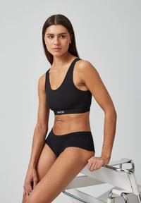 Zwarte katoenen sport-bh en bijpassende slip, met een ronde halslijn en logo-band, een gladde textuur, een aansluitend ontwerp en geen zichtbare naden.