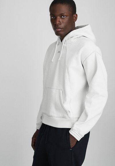 Hvid hættetrøje lavet af bomuldsblanding, med en frontlomme, ribbede manchetter og en justerbar snor. Minimalistisk design med kontrasterende syninger.