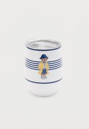 Fehér szigetelt pohár tengerészkék csíkokkal és egy sárga esőkabátot, kék sapkát és tornacipőt viselő medvével az oldalán, áttetsző fedéllel.