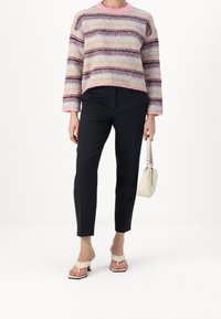 Sweter dzianinowy w wielokolorowe paski, różowy dekolt, czarne spodnie i kremowa torebka. Obuwie: beżowe klapki na obcasie, teksturowany materiał.