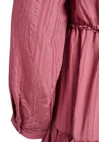 Vestido rosa texturizado con rayas verticales, cintura fruncida y mangas largas con diseño de puños. Tela suave y ligera con una silueta fluida.