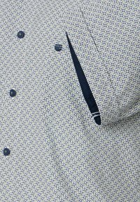 Blauw en wit gestippeld overhemd van stof met een gladde textuur. Voorzien van een zak, knopen en contrasterende donkerblauwe accenten.