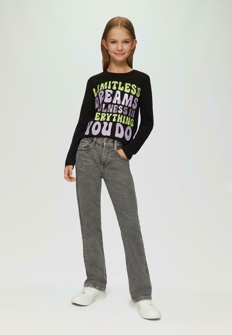 Schwarz langärmliges Shirt mit buntem Text; graue gerade Jeans; weiße Sneakers. Einfaches, lässiges Outfit mit modernem Design.
