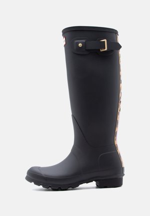 Botte de pluie haute en caoutchouc noir avec bride ajustable et détails imprimé léopard à l'arrière. Semelle robuste pour une meilleure traction.