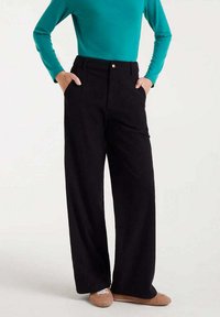 Pantalones de pierna ancha negros con una cintura alta y bolsillos delanteros, combinados con una blusa de manga larga turquesa. Tela suave y ajuste entallado.