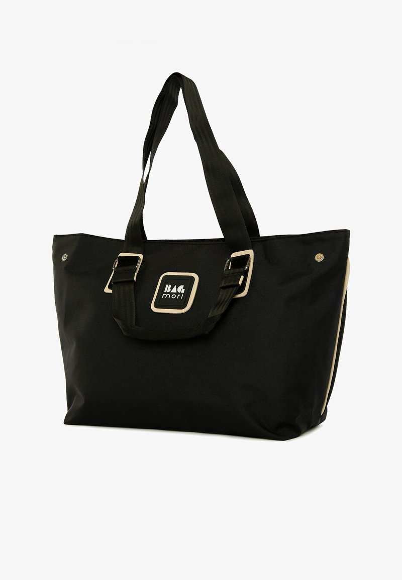 Fekete vászontáska, két erős fogantyúval, ezüst színű fém kiegészítőkkel és középen elhelyezett logóval. Oldalsó részletezéssel rendelkezik.