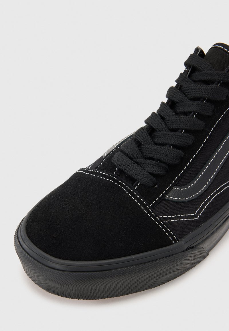 Czarne zamszowe sneakersy z zaokrąglonym noskiem, teksturowaną czarną gumową podeszwą, czarnymi sznurowadłami i białymi detalami stębnowania. Zawierają szare akcenty.