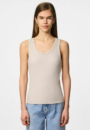 Top de tirantes de canalé color beige con escote redondeado y tirantes anchos, combinado con jeans de mezclilla azul claro. Tejido suave con una silueta ajustada.