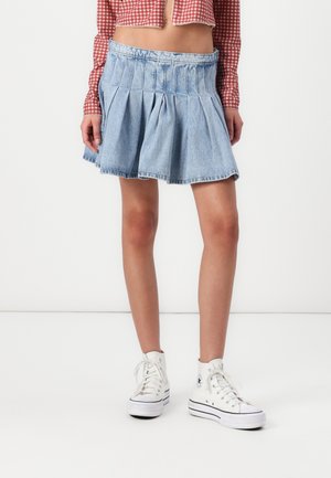 Denim skirt, light blue, pleated design, mid-thigh length, features a wide waistband; worn with white high-top sneakers.