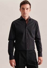 Zwart shirt met lange mouwen, een button-down kraag, een enkele borstzak en een knoopsluiting aan de voorkant. Gladde stof met een getailleerde pasvorm.