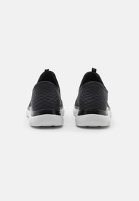 Black slip-on shoes featuring a textured upper with a diamond pattern, contrasting black heel, and white sole. No visible branding.