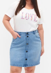 Jeanskjol med hög midja, ljusblå färg, framficka och svarta knappar. Matchad med en vit t-shirt med färgglada blommiga bokstäver.