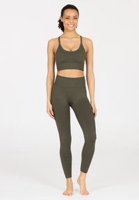 Olivegrünes, passendes Sport-BH- und Leggings-Set aus weichem, dehnbarem Material. Der BH hat dünne Träger; die Leggings sind mit hohem Bund und eng anliegender Passform gestaltet.