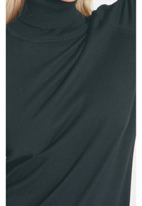 Mustat korkeakauluksiset villapaidat ribbikuvioilla, joissa on istuva muotoilu ja hihoissa hieman valuva kangas.