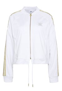 Witte jas met ritssluiting en gouden accenten, uitgevoerd in een cropped ontwerp met geribde manchetten en een geborduurd logo op de borst.