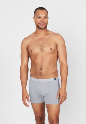 Grijze boxershorts met een elastische tailleband met een zwart logo; gladde stof, getailleerd ontwerp, lengte tot halverwege de dij.