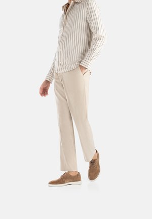 Gestreiftes, beige und braunes Langarmhemd, beige Hose und braune Wildlederschuhe. Slim-Fit, taillierter Schnitt mit sichtbaren Taschen.