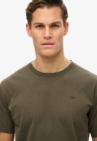 Olivengrøn kortærmet t-shirt lavet af blødt bomuld, med rund halsudskæring og et lille broderet logo på brystet.