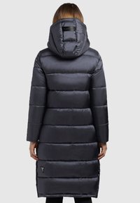 Abrigo de pluma negro con capucha desmontable, con un diseño acolchado, mangas largas y bolsillos laterales con cremallera. Tejido texturizado con un acabado suave.