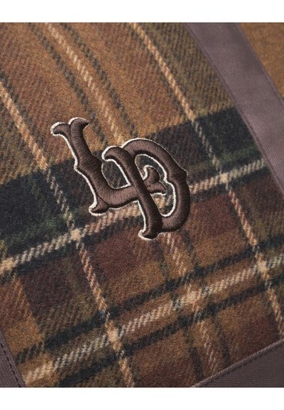 Tissu en laine à damier marron avec un logo brodé sombre. Le design comprend des nuances de vert et de beige dans le motif à carreaux.