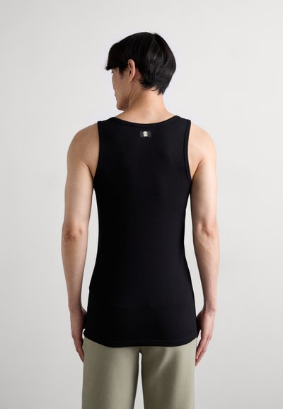 Must värvi puuvillane tank top ümmarguse kaelusega, tagaküljel on väike plaastrike. Koos heledates värvides lõdva lõikega pükstega.
