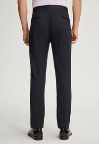 Marinefarbene Anzughosen mit slim Fit, flachem Bund, zwei Gesäßtaschen und glatter Textur. Abgerundet mit dezenten Gürtelschlaufen und einem eleganten Taillenbund.