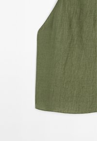 Grøn linnedtunika med en blød, tekstureret finish. Har en buet kant og brede ærmegab, der fremhæver et let design.
