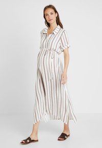 Vestido de maternidade listrado em branco e vermelho, com gola, mangas curtas dobradas, cintura com cinto e uma bainha fluida.
