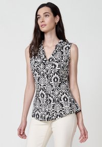 Blusa senza maniche in bianco e nero con motivo floreale damascato; presenta un colletto a scollatura a V e una chiusura con bottoni; realizzata in un tessuto leggero.