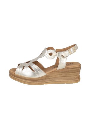 Sandalia de cuña de cuero plateado con puntera abierta, diseño recortado, correa en el tobillo y cierre de hebilla sobre una suela plataforma de madera texturizada.